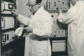 Turning a knob on the 512-channel gamma spectrometer donated to the laboratory by Finland, is Otto Suschny, head of the Environmental Radioactivity Section. The new instrument makes possible the simultaneous and rapid determination of several radionuclides in up to four samples at a time and will help save time analysing samples for scientific and health protection purposes.  In the background: Herbert Frittum, IAEA staff member.  April 1964. Please credit IAEA 